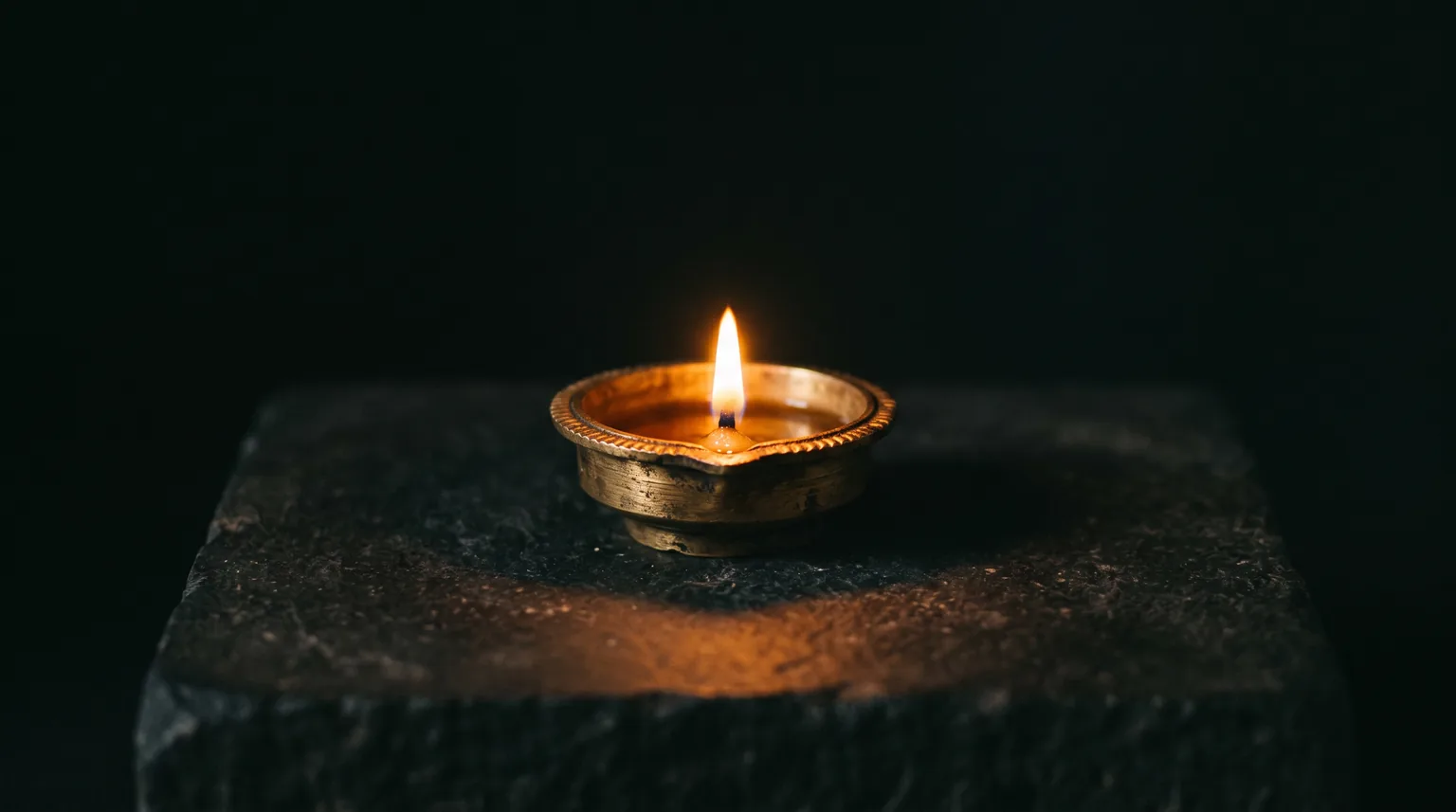 A brass lamp, lit, on a dark evening.
